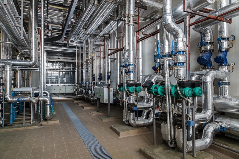 Industrial boiler interior with lots of pipes, pumps and valves.